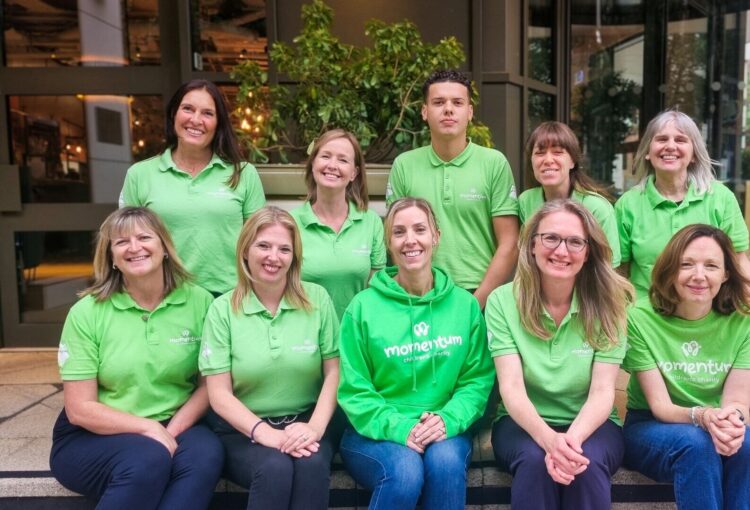 A photo of 10 Momentum Children's Charity employees wearing green, branded tops.